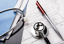 stethoscope and pen resting on a sheet of medical lab test results