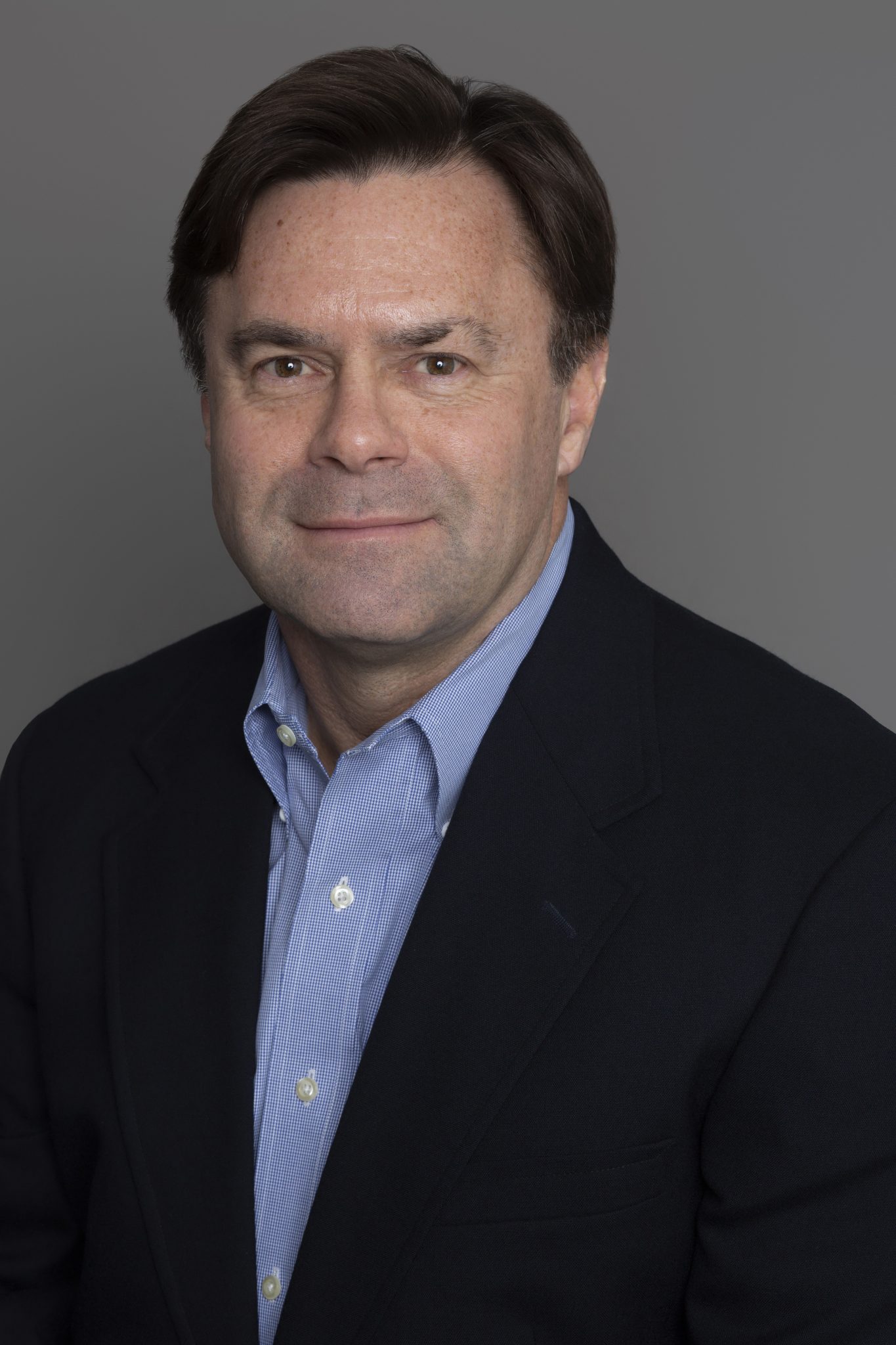 Roger Lee headshot - Wearing a suit jacket and a blue dress shirt