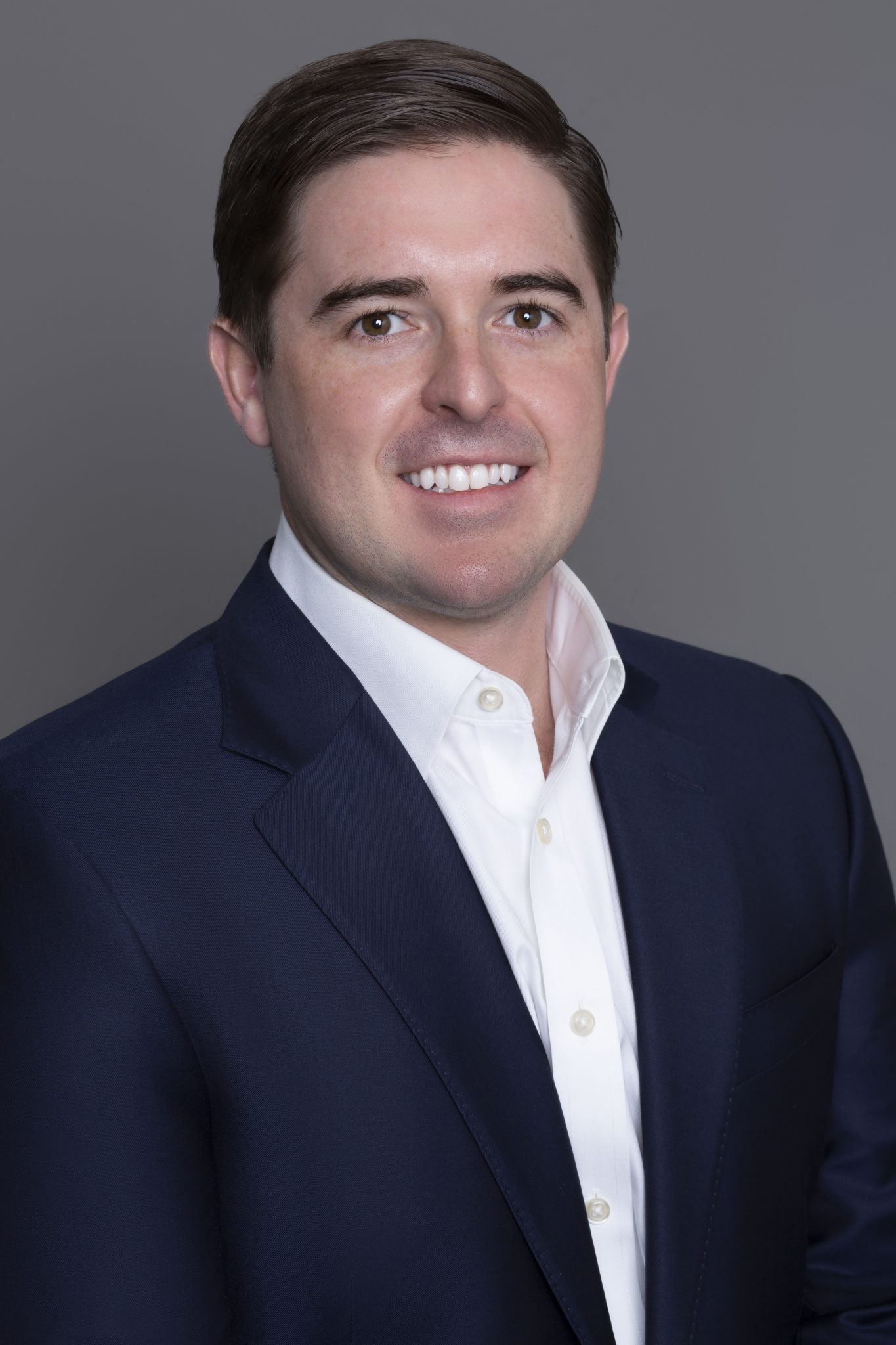 Thomas Burke headshot - wearing a dark blue suit jacket and a white dress shirt